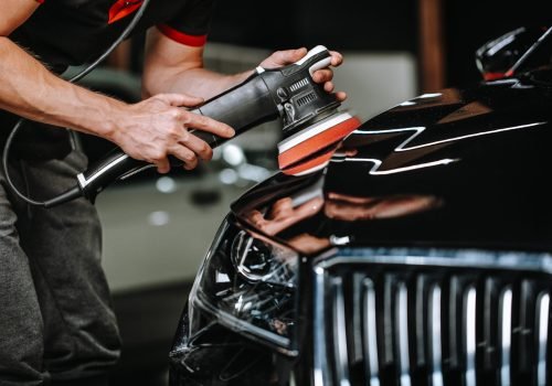 Professional process of detailing car in car studio, hands with orbital polisher, scratching remover, vehicle care concept